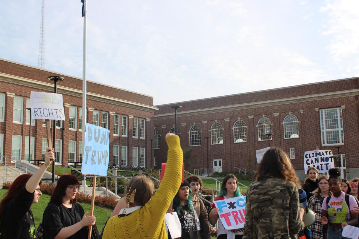 Students protesting in front of Benson Polytechnic High School, with signs that say "LGBTQ+ Rights";, "Dump Trump", "Fuck Trump", and "Climate Cannot Wait."