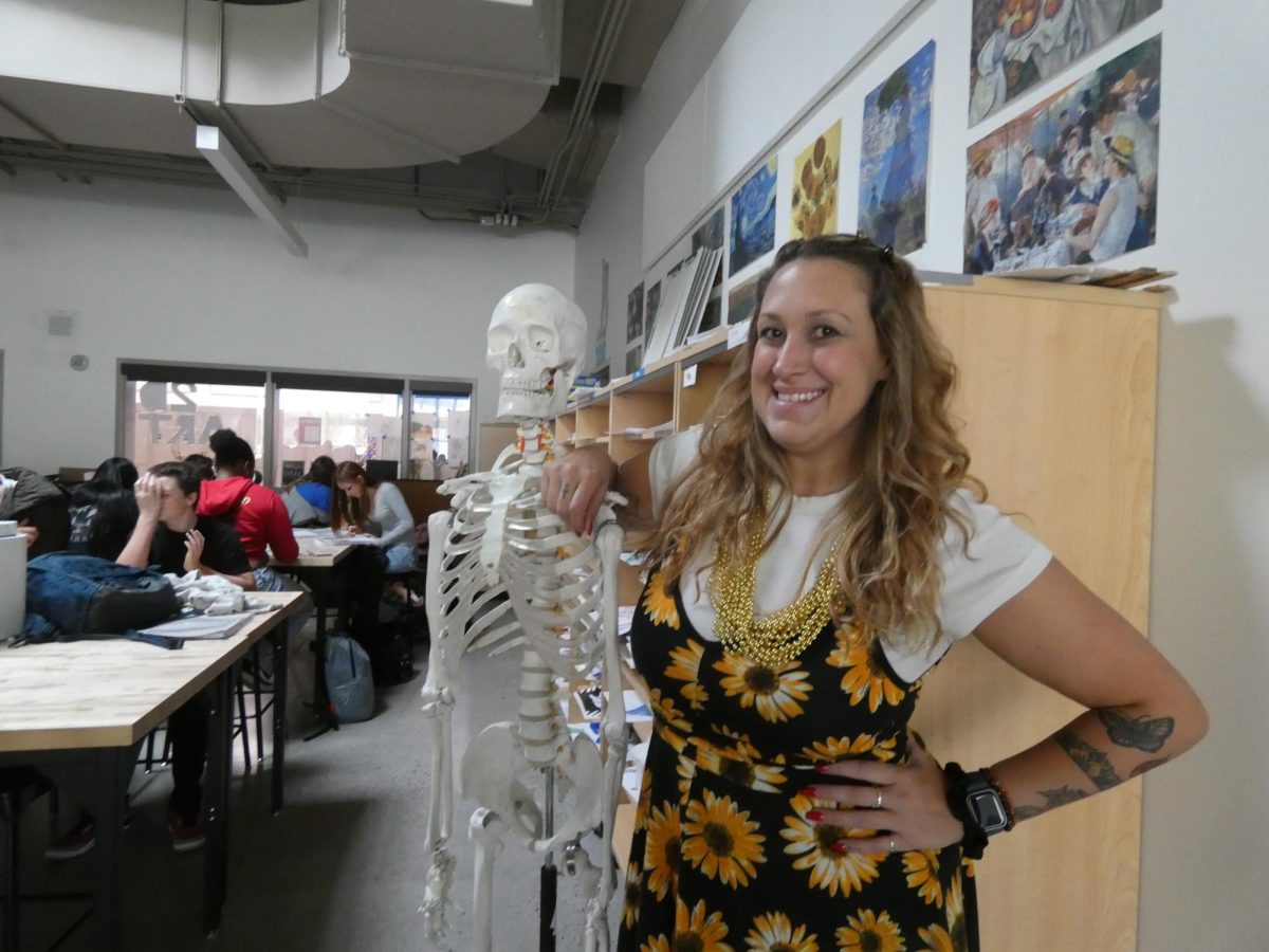 Torin King poses with a skeleton model in her Art classroom.